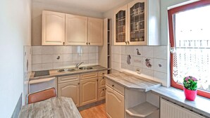 A compact kitchen with a dining table, built-in cabinets, and a window with a plant. - 2 bedroom cozy home in Eggesin (Eggesin)
