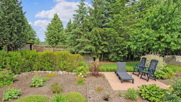 A garden with a bench and two chairs, surrounded by various plants and trees. - 2 bedroom cozy home in Eggesin (Eggesin)