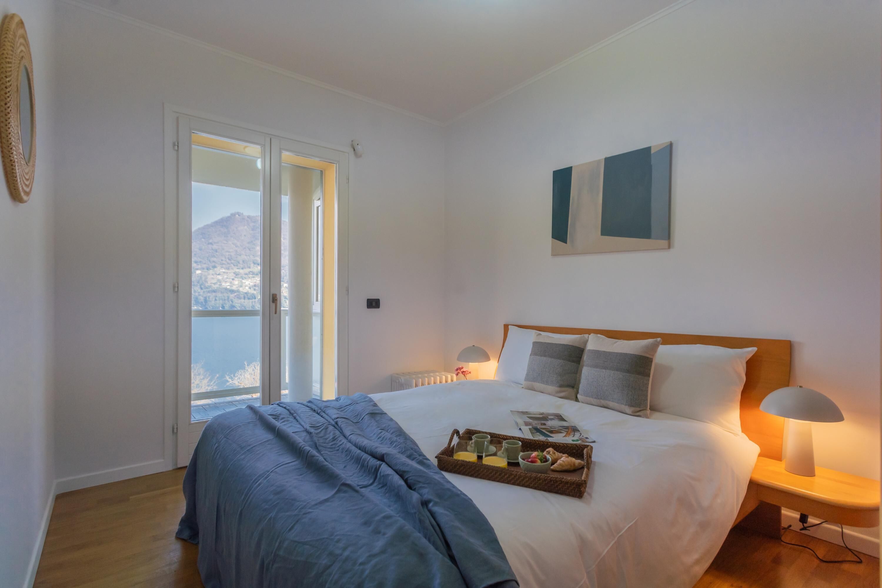 Una camera da letto con un letto, un comodino, una lampada e un vassoio con cose per la colazione.