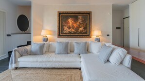 Ein modernes Wohnzimmer mit einem großen Ecksofa, zwei Beistelltischen und einem gerahmten Gemälde an der Wand.
