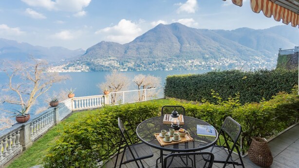 Eine Terrasse mit nachgestelltem Tisch für Tee, mit Blick auf einen See und Berge.