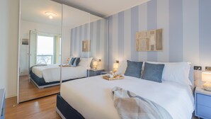 Ein modernes Hotelzimmer mit einem großen Bett, Nachttischen, einem Spiegel und Blick ins Freie.