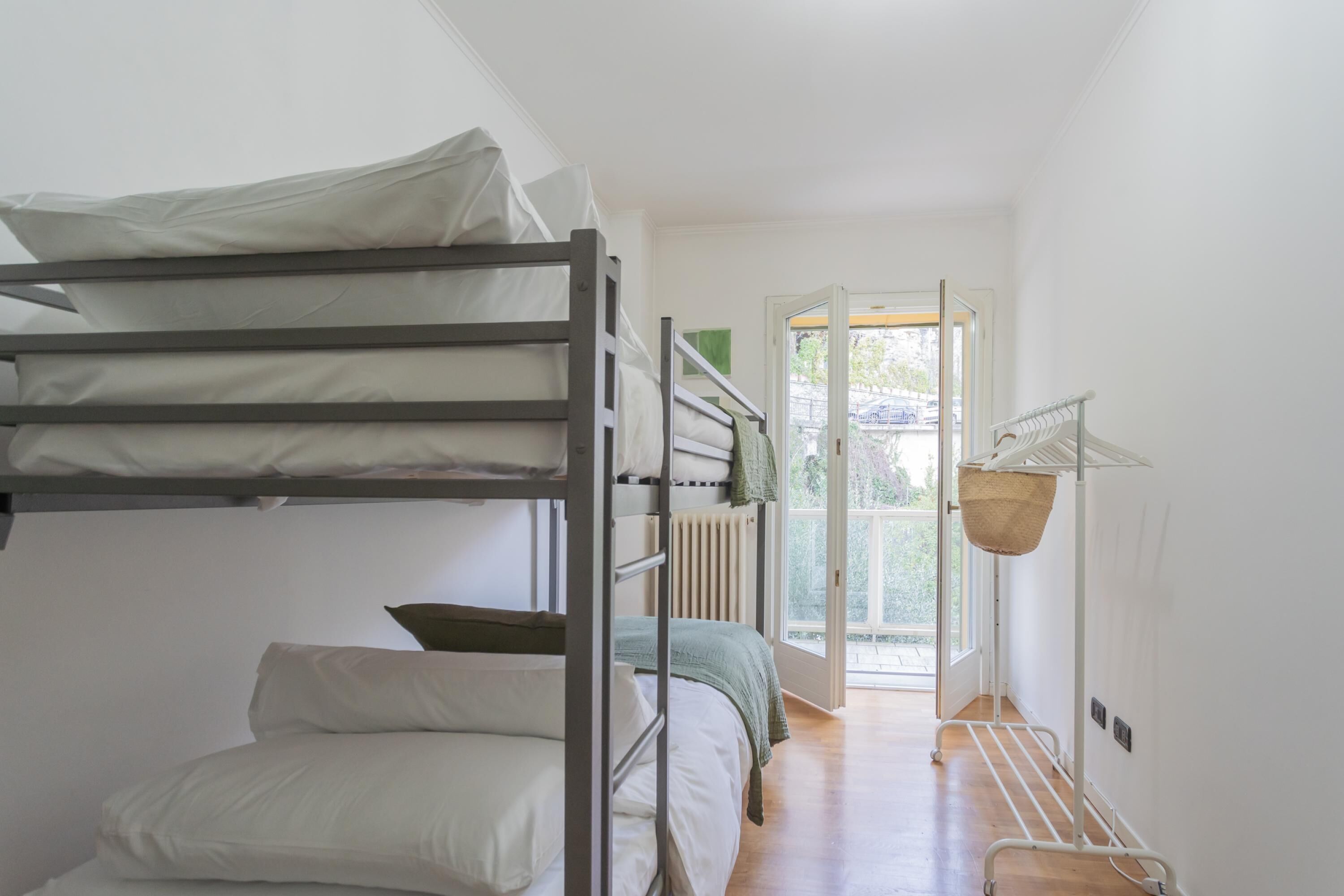 A dormitory-style room with bunk beds, a radiator, and a view through an open door.