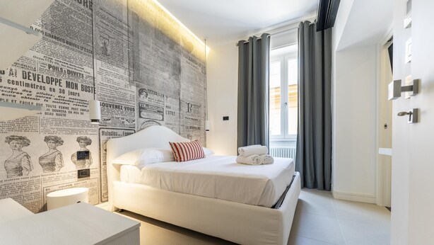 Une chambre à coucher moderne avec un grand lit, une table de chevet et un mur recouvert de coupures de journaux.