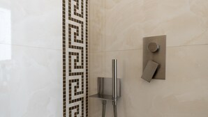 Une salle de bain moderne dotée d’une douche, d’un panneau de commande mural et d’un motif décoratif en carreaux sur le mur.