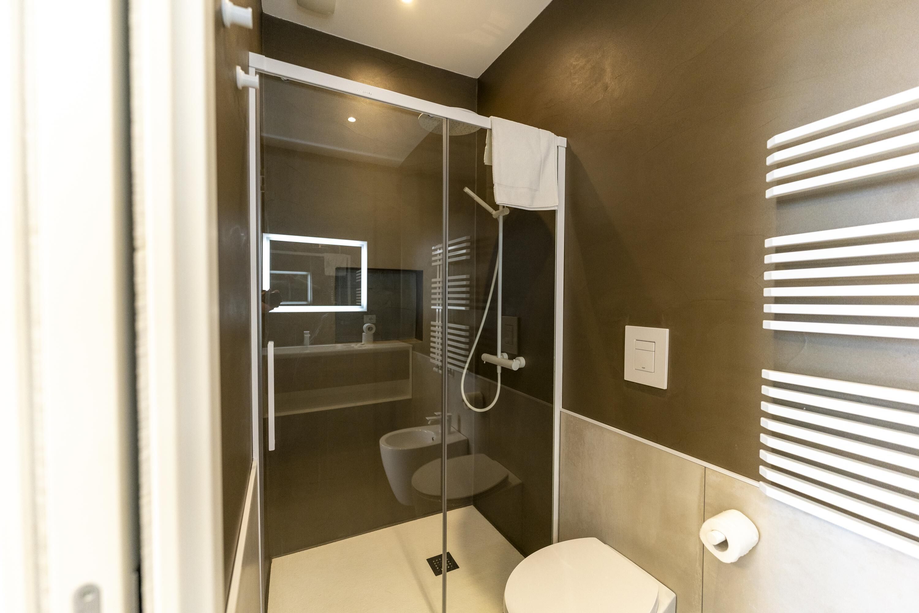 A modern bathroom with a glass-enclosed shower, a toilet, and a bidet.
