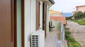 A coastal building with a tiled patio, a door, and an air conditioning unit. - Sa Pedrera in Sa Rocca Tunda (San Vero Milis)
