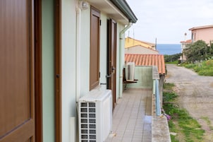 Un edificio frente al mar con un patio empinado, una puerta y un equipo de aire acondicionado.