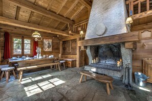 A rustic wooden interior with a stone fireplace, wooden benches, and a long dining table. - Chalet 155sqm | 360View | Quiet | Bus & Train 150m (Chamonix-Mont-Blanc)