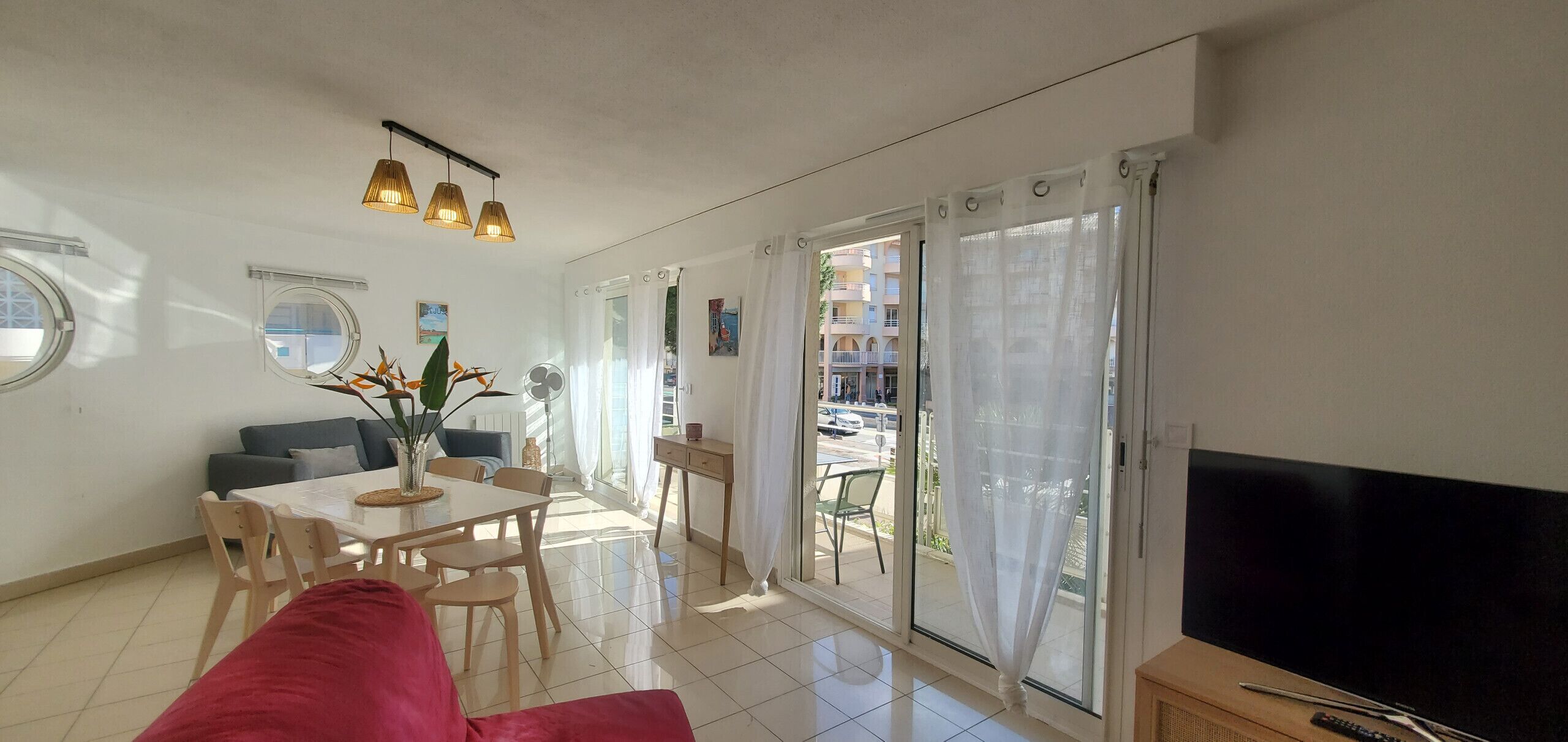 Una sala de estar moderna con comedor, puertas correderas de vidrio y un televisor de pantalla plana.
