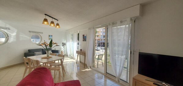 A modern living room with a dining area, large sliding glass doors, and a flat-screen TV.