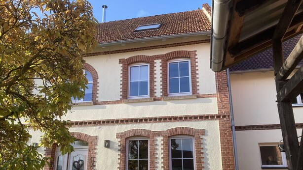Un bâtiment à deux étages, doté d’une façade en briques, de nombreuses fenêtres et d’une cheminée bien visible.
