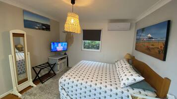 Une chambre à coucher avec un lit, une télévision, un miroir, une fenêtre et des œuvres d’art accrochées aux murs.