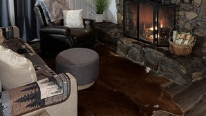 A cozy living room with a stone fireplace, leather seating, and a flat-screen TV. - Peaceful and secluded getaway in Saline County  (Benton)