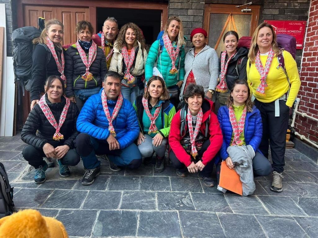 Un grupo de personas posando frente a un edificio con fachada de ladrillo y una puerta.