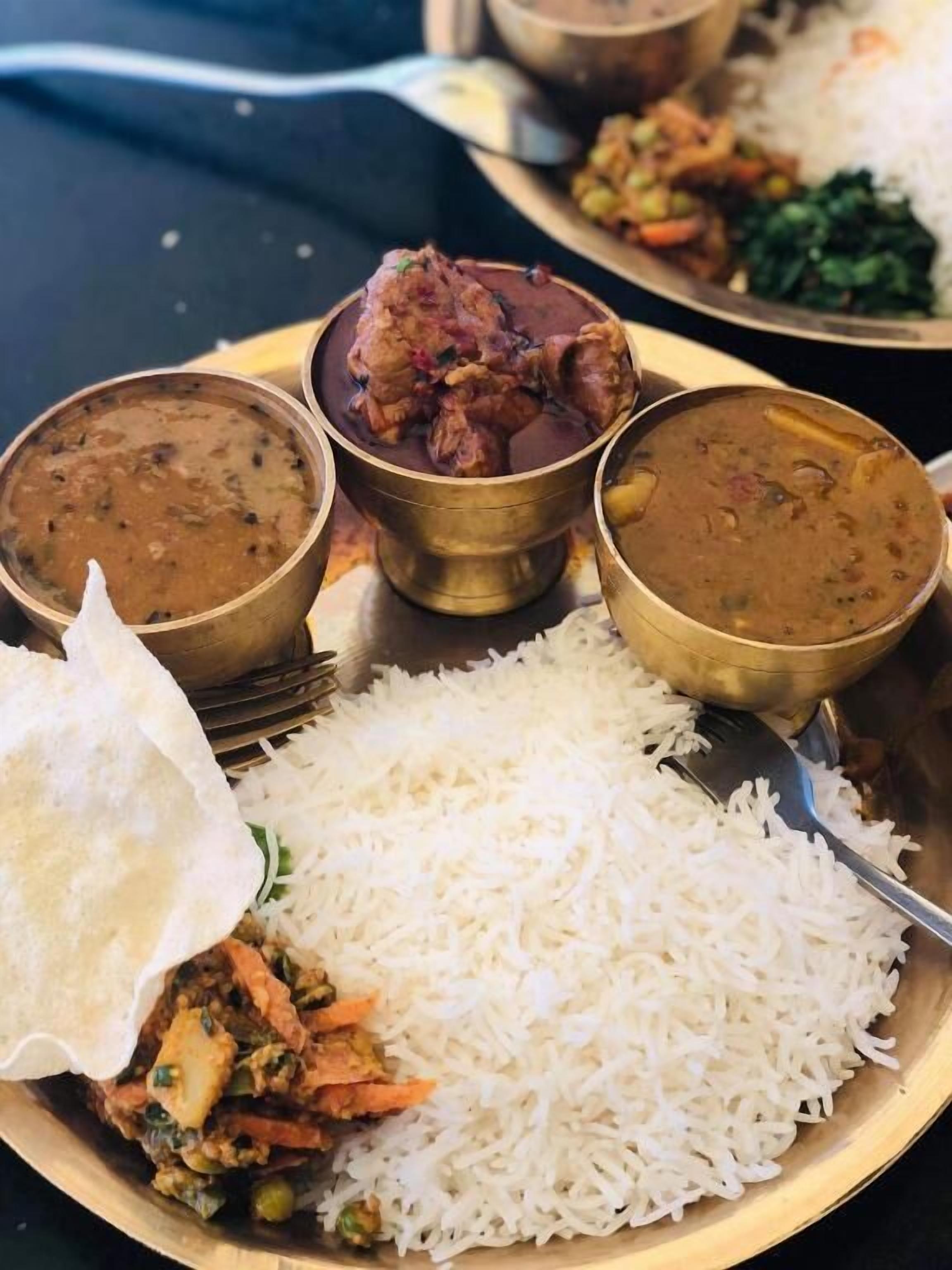 Un piatto di riso bianco, un curry di verdure e due ciotole di dal.