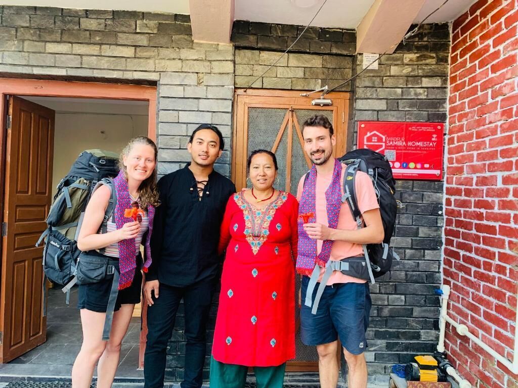 A group of people standing in front of a building with a sign that reads "AMIRA HOMESTAY".