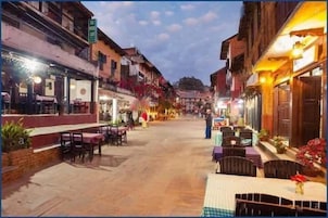 Una calle con mesas al aire libre, edificios y un letrero de cafetería.