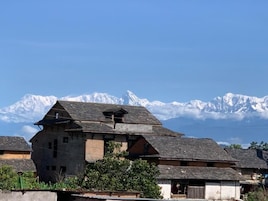 Un edificio de estilo chalé tradicional con techo inclinado, rodeado de construcciones similares, con montañas nevadas al fondo.