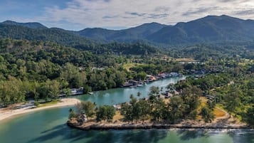 A coastal town with a river, surrounded by mountains and dense forests.