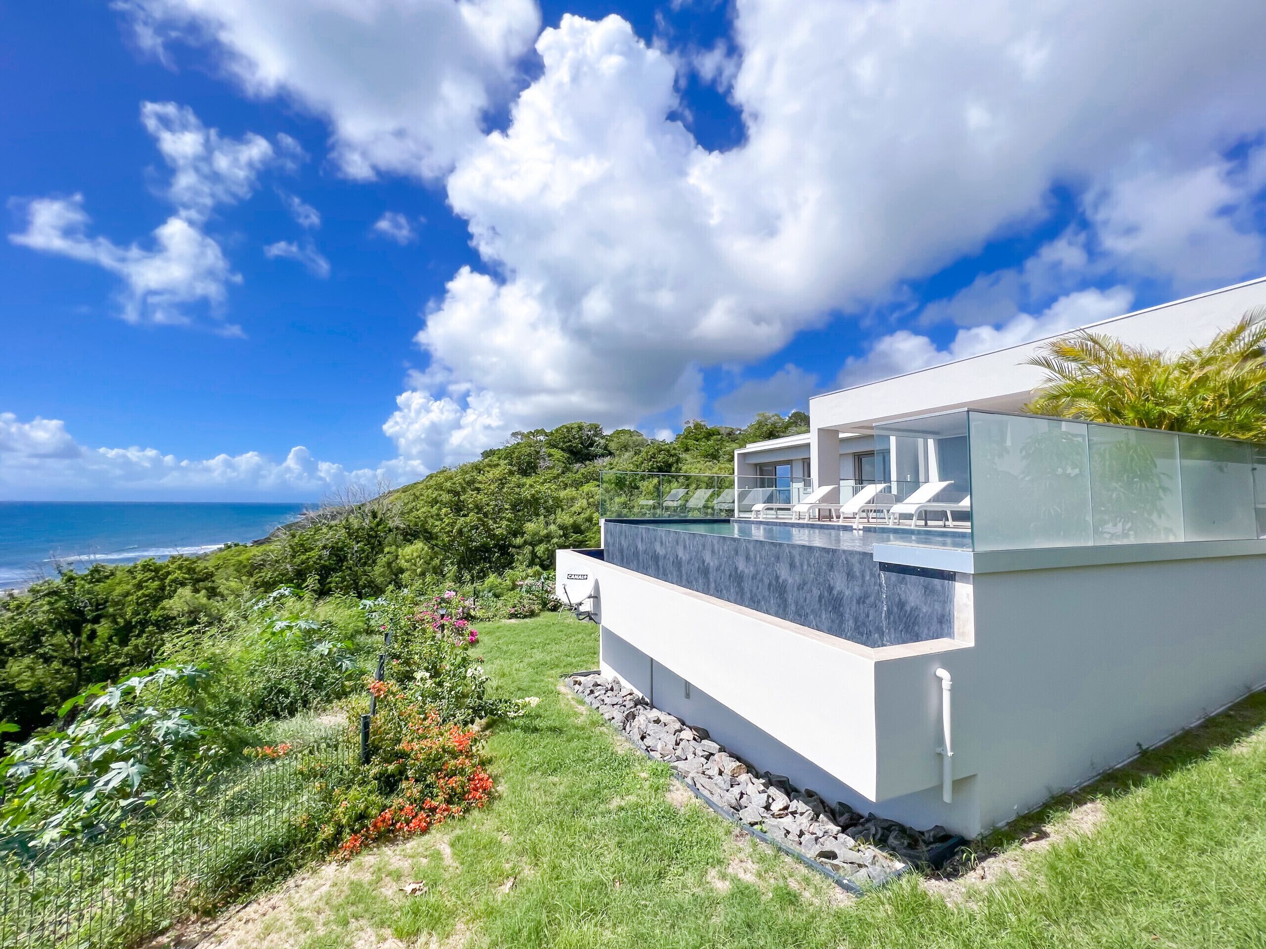 A modern house with a pool, overlooking a coastal landscape.