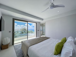 Une chambre moderne avec un grand lit, un ventilateur de plafond et un balcon avec vue.