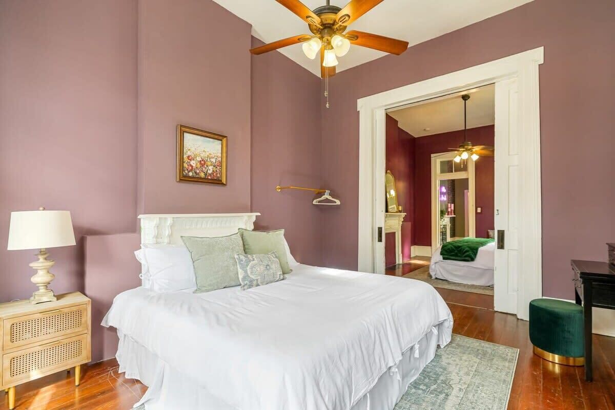 A bedroom with a bed, a ceiling fan, a bedside table, and a hanging light fixture.