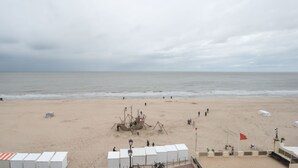 A beach with a lifeguard tower, a lifebuoy, and a flag. - Koekoeksnest Penthouse at the beach by Interhome (De Haan)
