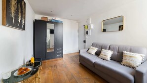 A modern living room with a grey sofa, a glass coffee table, and a black wardrobe.