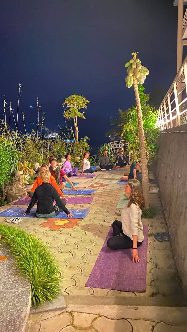 A group of people practicing yoga outdoors at night on patterned mats.