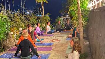 A group of people practicing yoga outdoors at night on patterned mats.