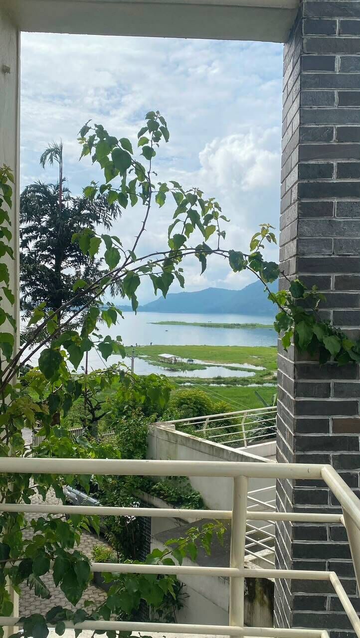 A view from a balcony with a railing, overlooking a body of water and greenery.