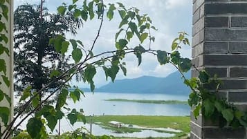 A view from a balcony with a railing, overlooking a body of water and greenery.