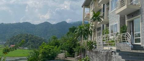 Ein Hotel mit Schwimmbad, Bergblick und einem Balkon mit Geländer.