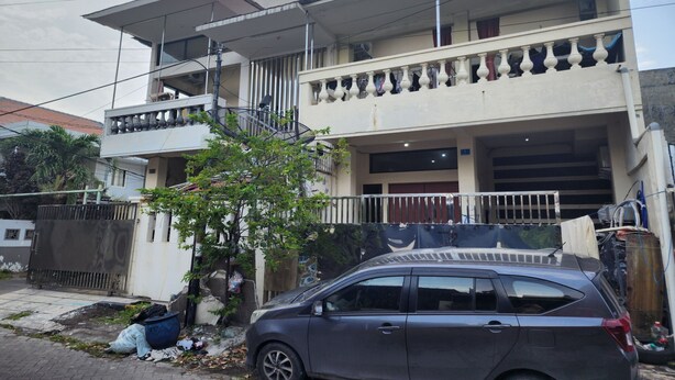 A two-story building with a balcony on the upper floor and a garage on the ground floor. - OYO 93865 Dv Homestay Syariah Kupang (Surabaya)