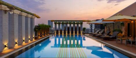 Alberca al aire libre, sombrillas en la alberca y camastros