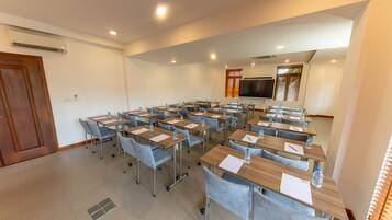 Une salle de conférence équipée de plusieurs tables et chaises, d’un téléviseur à écran plat et d’un système de climatisation.