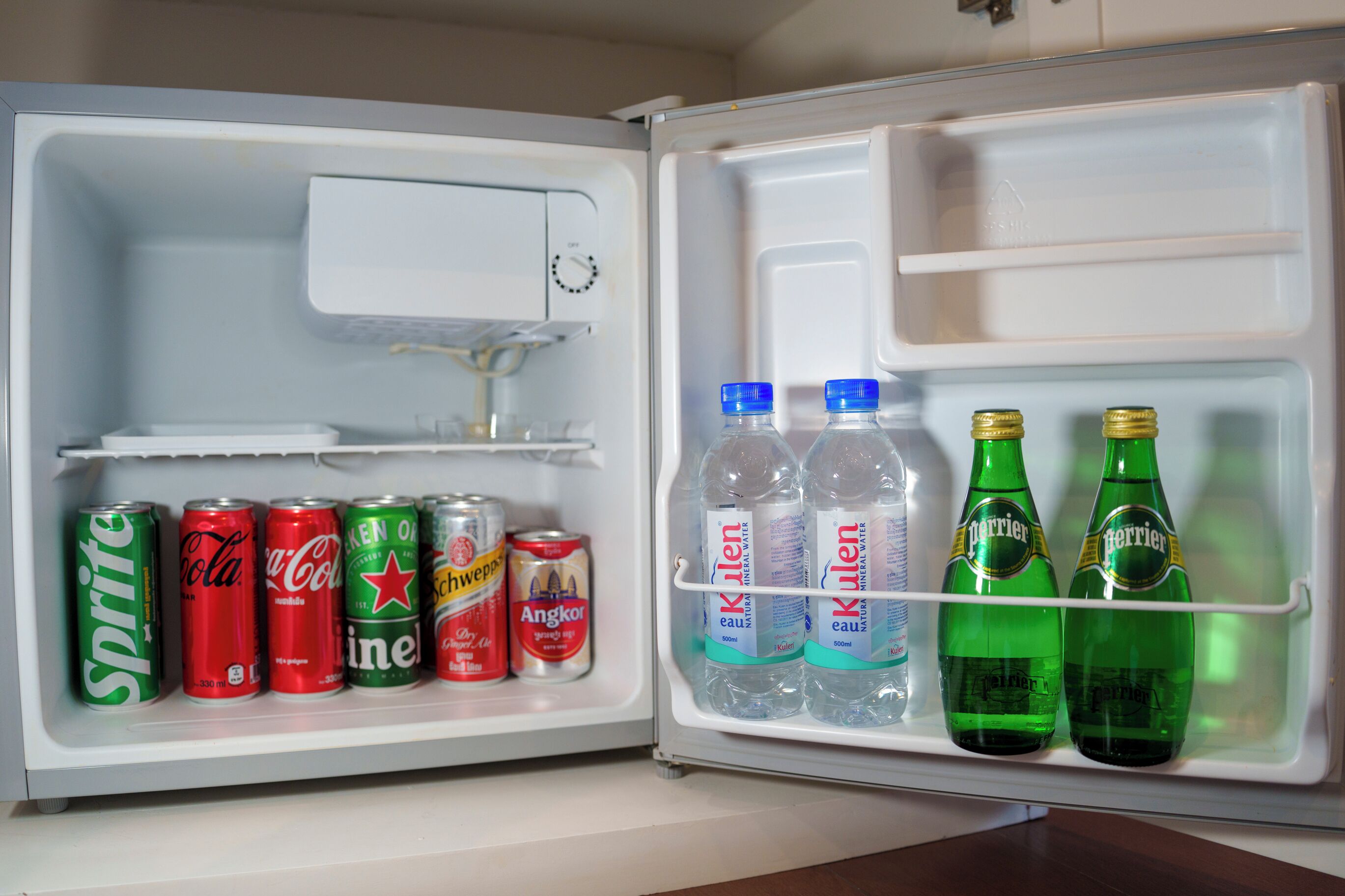 Un refrigerador abierto con bebidas y latas.