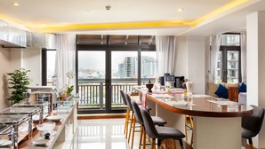 A modern kitchen with a dining area, large windows, and a city view. - Jaya Suites Hotel (Phnom Penh)