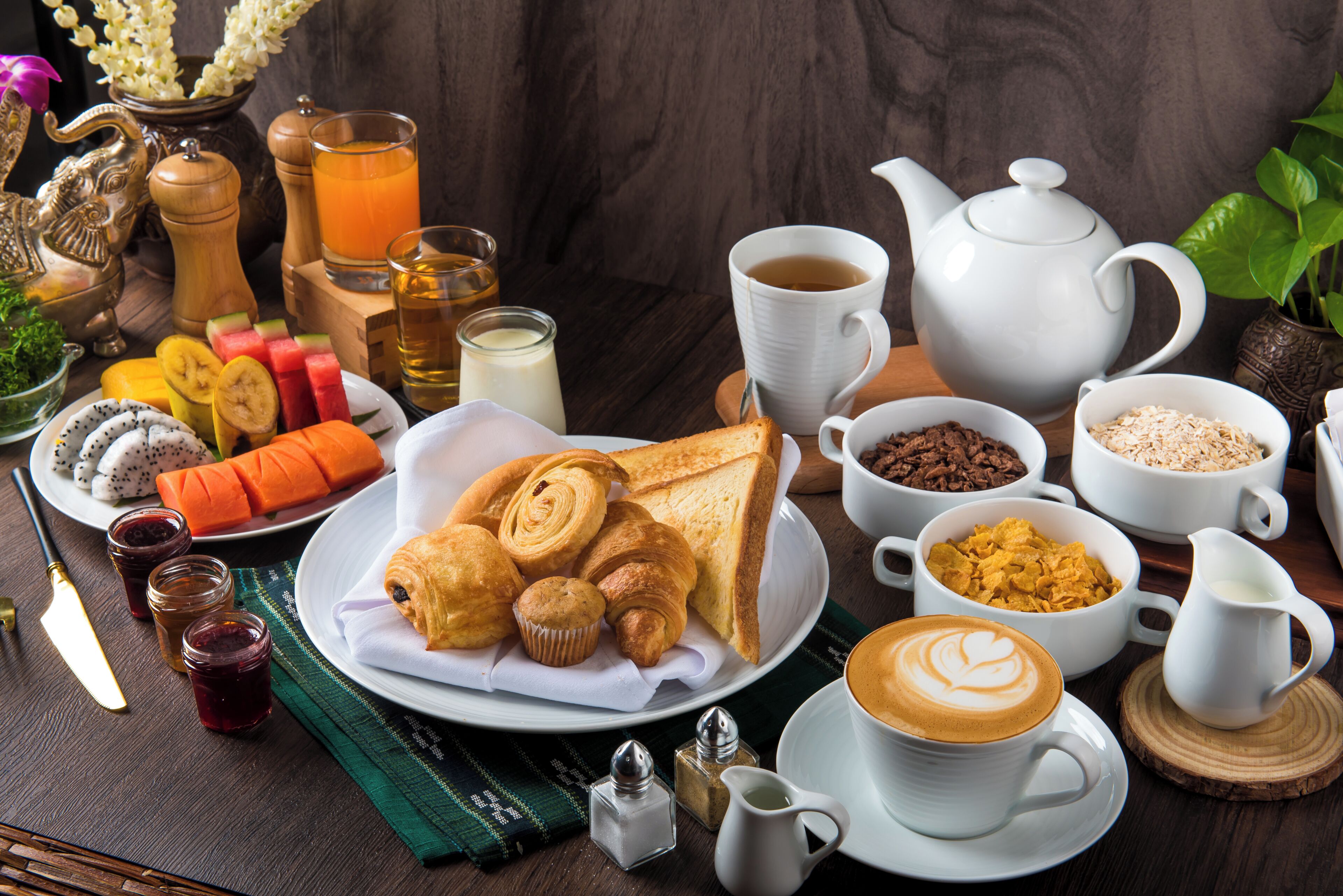 Una escena de desayuno con diversos alimentos, una tetera y una taza de café.