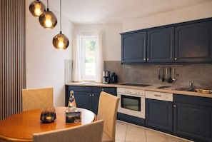 Una cocina moderna con armarios oscuros, una mesa redonda para comer e iluminación colgante.
