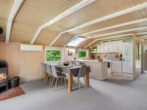 Une cuisine moderne dotée d’un îlot central, d’un coin repas avec des chaises et d’une cheminée.
