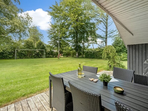 An outdoor dining area with a table and chairs, a bottle, and a bowl.