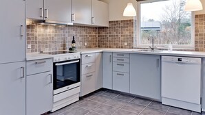 A modern kitchen with grey cabinets, a tiled backsplash, a built-in oven, and a window with a view of trees. - "Sada" - 12km from the sea by Interhome (Oksbøl)