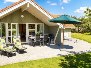 A house with a patio area featuring outdoor furniture and a green umbrella.