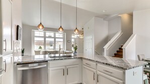 A modern kitchen with white cabinetry, a granite countertop, and pendant lighting. - Spokane Valley Home w/ Fire Pit - 1 Mi to Trails! (Spokane Valley)