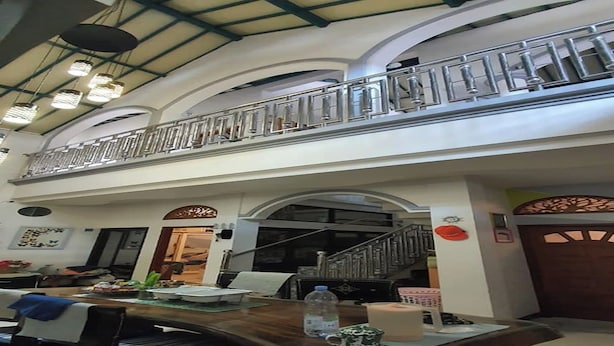 A dining area with a wooden table, chairs, and a balcony with a railing. - Hotel O Cprc Inn Serpong (Cisauk)