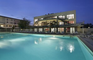 Een modern hotel met een zwembad, buitenterras en een trap naar de bovenverdiepingen.