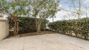 A paved outdoor area with trees and a hedge. - Large terrace, Appt 4 pers - near the beach (Agde)