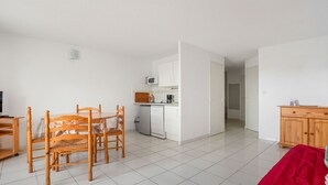 A compact living space with a dining table, chairs, a kitchenette, a TV, and a wardrobe. - Large terrace, Appt 4 pers - near the beach (Agde)